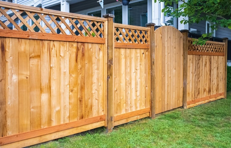 Nice wooden fence around house. Wooden fence with green lawn.
