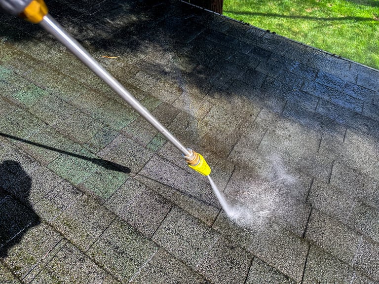 Pressure washer being used to clean a roof on a clear day
