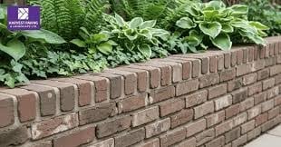 Red brick garden wall with green foliage and plants growing above it