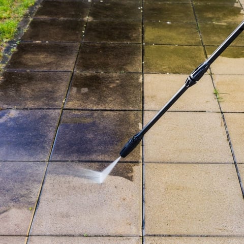 High-pressure water jet cleaning moss and algae from patio pavers